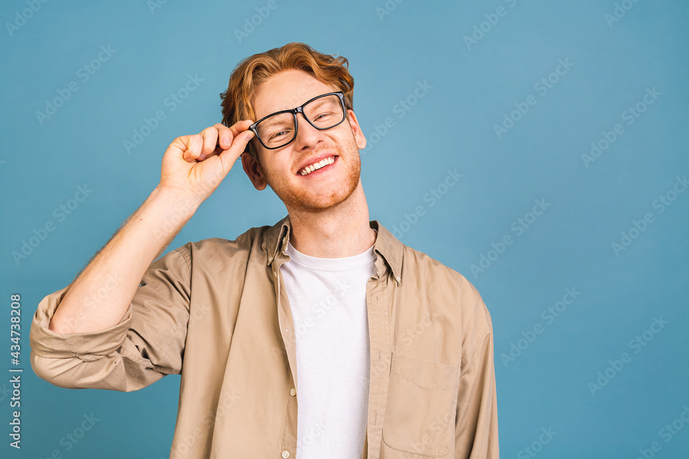 Headshot of attractive red-haired caucasian young business man wearing casual and glasses, isolated on blue background. Headshot of attractive red-haired caucasian young business man wearing casual and glasses, isolated on blue background.