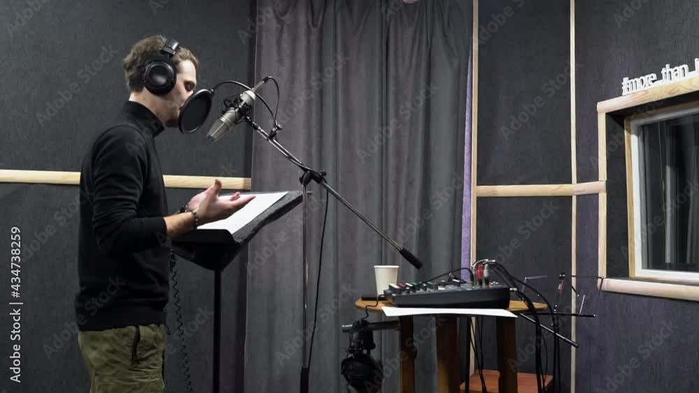 Voice actor in headphones on recording studio ask director way to play his role. Expressive scene of concentration near the microphone Voice actor in headphones on recording studio ask director way to play his role. Expressive scene of concentration near the microphone