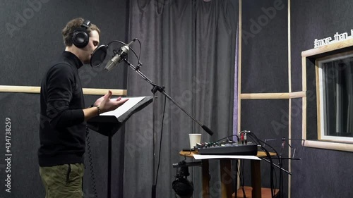 Voice actor in headphones on recording studio ask director way to play his role. Expressive scene of concentration near the microphone 