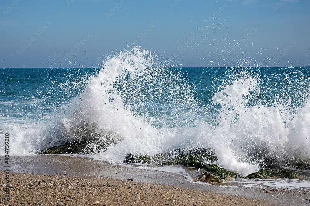 Gischt einer auf Felsen aufschlagende Welle an einem Strand in Barcelona II