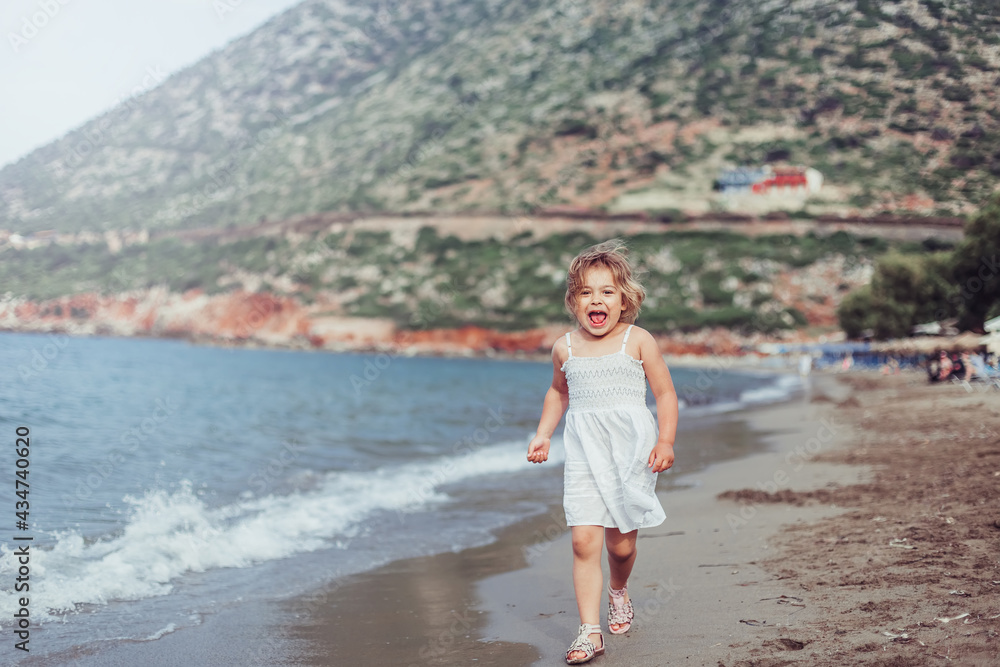 Little adorable girl plays on sea coast. Summer time, vacation concept