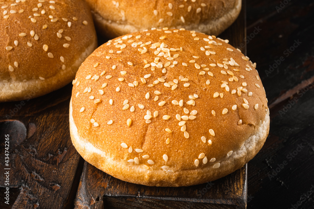 Hamburger buns with sesame, on wooden serving board, on old dark  wooden table background