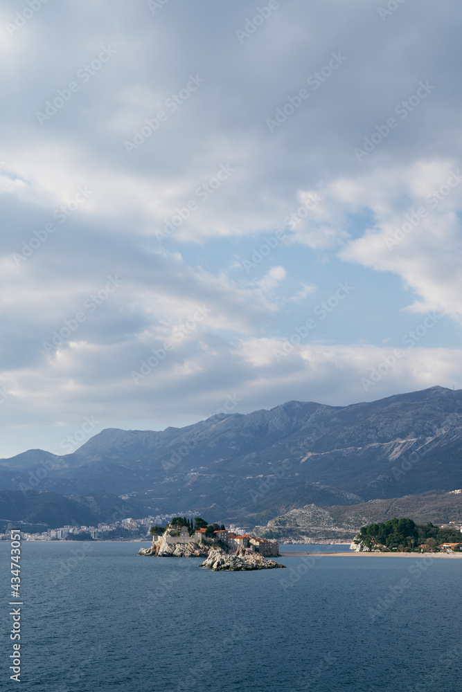 View from the sea to Sveti Stefan island against the background of mountains, Montenegro