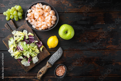 Healthy lifestyle - cooking of fresh salad of prawn, green salad, olive, with sauce apple and grape, on old dark wooden table , top view flat lay, with copy space for text