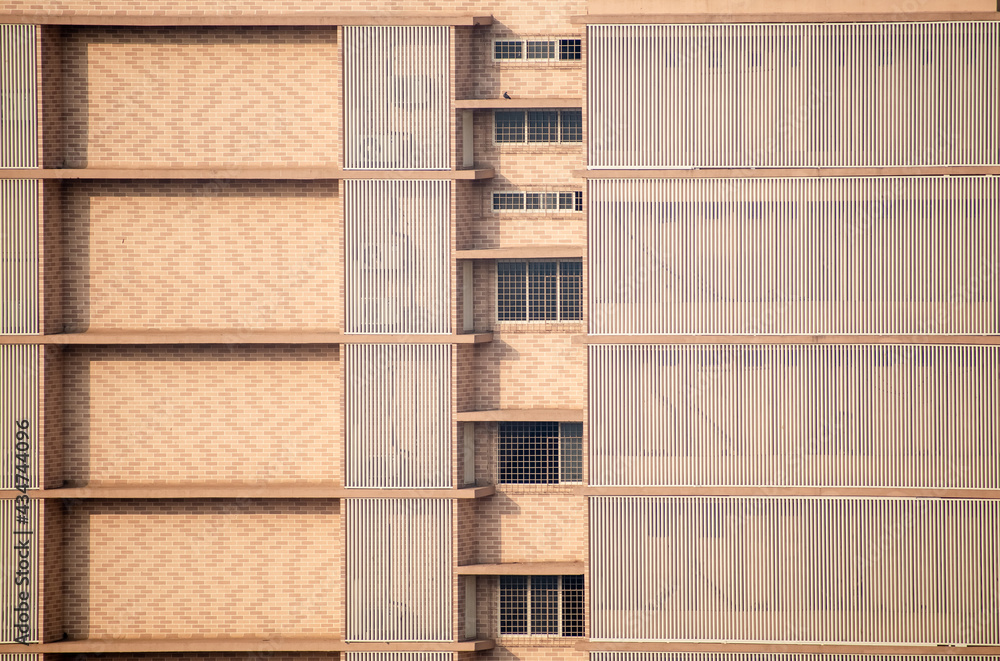Clean geometric wall colored beige of a high rise building with windows of houses in suburban Mumbai. Clean geometric wall colored beige of a high rise building with windows of houses in suburban Mumbai.