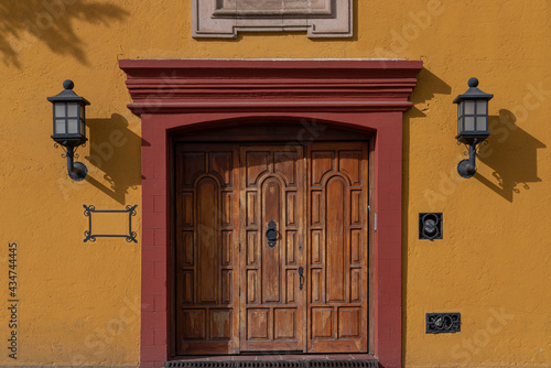 A yellow wall and a beautiful wooden door in Mexico. Traditional Mexican exterior photo