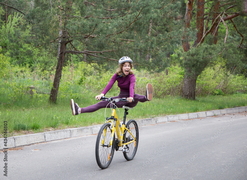 funny portrait of an emotional girl in a helmet on a bicycle in motion. having fun riding a bike with his feet off the pedals. healthy active lifestyle. outdoor cycling