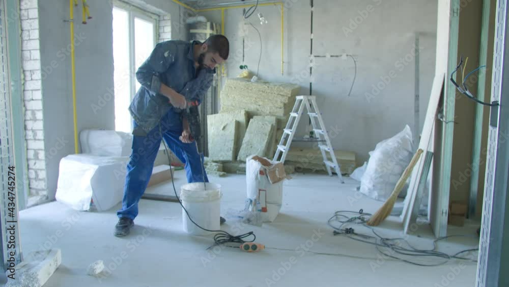 Male builder mixing stucco with drill in bucket Male builder mixing stucco with drill in bucket