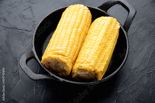 Delicious juicy sweet boiled corn , on black stone background