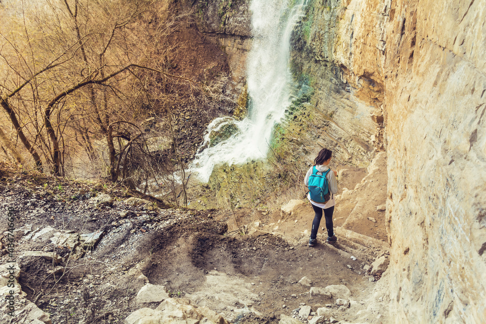 Young Tourist Woman Walking  in the Mountain Looking a Spring Waterfall