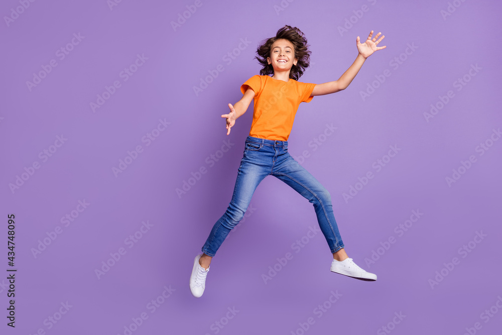 Full length body size view of attractive carefree cheerful boy jumping having fun isolated over violet purple color background Full length body size view of attractive carefree cheerful boy jumping having fun isolated over violet purple color background