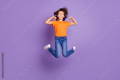 Full length body size photo cheerful schoolboy jumping up showing biceps isolated purple color background