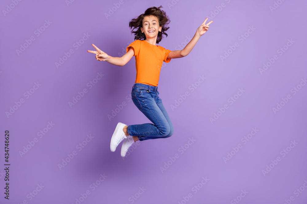 Full length body size view of attractive cheerful boy jumping showing v-sign isolated over violet purple color background