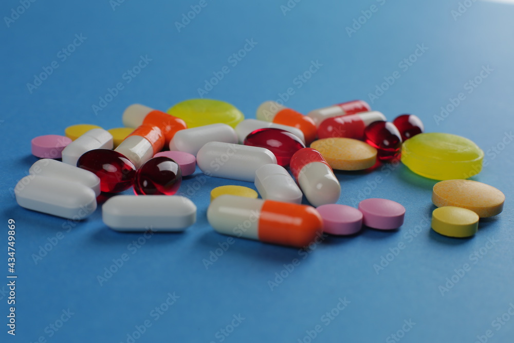Multicolored medical pills of various shapes on a blue background Multicolored medical pills of various shapes on a blue background