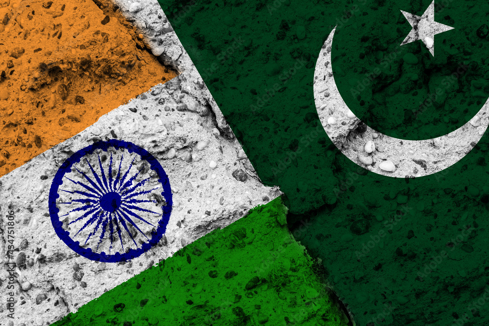 Concept of a Conflict between India and Pakistan with painted flags on a wall with a crack