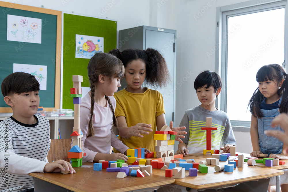 Diversity of school students playing wooden blocks in classroom