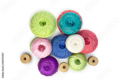Multicolored balls and bobbins of woolen yarn, wooden thread sleeves on white isolated background. Needlework, handmade. view from above. Isolated. Copy space