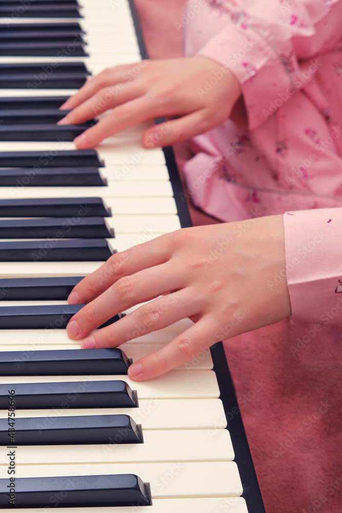 A woman is engaged in music sitting at a synthesizer on a home bed, hands close-up A woman is engaged in music sitting at a synthesizer on a home bed, hands close-up