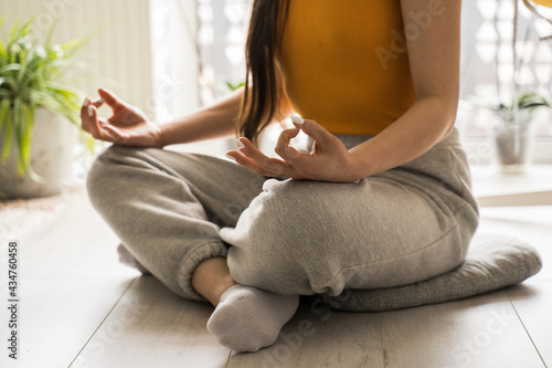Mindful girl sitting cross-legged at the floor, practicing yoga and enjoying meditation