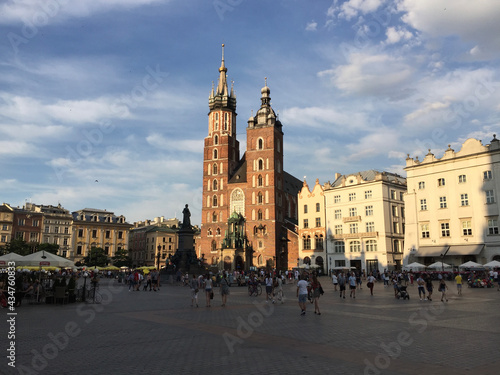View of the St. Mary's Basilica, a Brick Gothic church adjacent to the Main Market Square in Kraków, Poland. The Adam Mickiewicz Monument can be seen in front of the church.