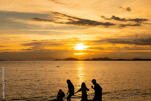 Group of happy kids playing on beach at the sunrise time.