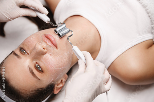 Photos Woman at beauty clinic lying on therapy table, beautician in gloves uses galvani