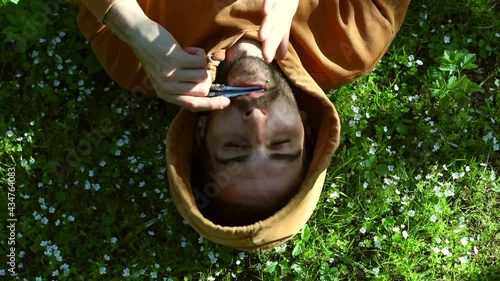 Close up of young happy man resting on forest white flowers playing on vargan authentic ethnic music. Sunny background. Musician artist relaxing outdoors. Green tourism. Eco traveling concept.  photo