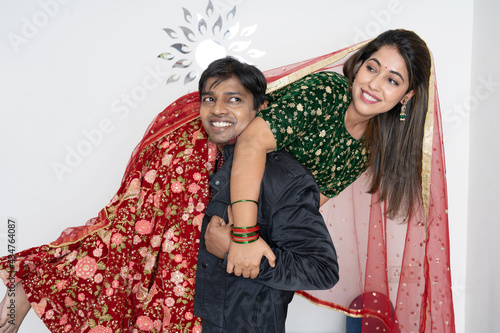 Man carrying woman on shoulder. Husband and wife. Happy and smiling. Grey background.