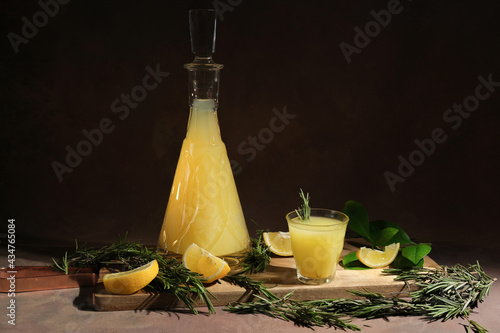 Alcoholic drink limoncello. Shot glass of Italian lemon liqour, fresh lemons and limoncello decanter on table.