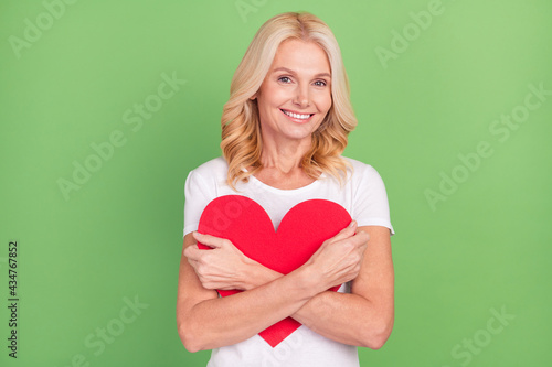 Photo portrait elder woman smiling embracing heart on valentines day isolated on pastel green color background