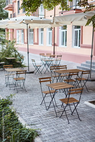 table and chairs on the terrace empty street cafe with garden © ShapeImages