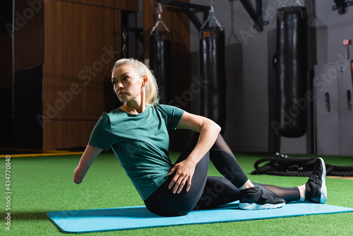 Quadro su tela amputee sportswoman working out on fitness mat in gym