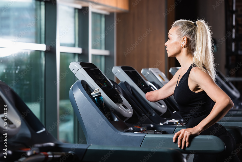 woman with amputated forearm exercising on treadmill in gym woman with amputated forearm exercising on treadmill in gym