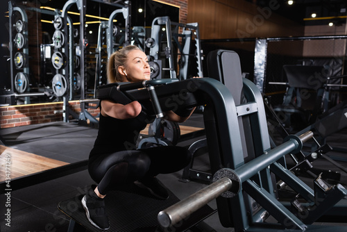 strong-willed amputee woman working out on exercise machine in gym