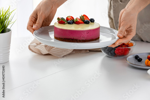 Decoration of vegetarian dessert  cake with berries. Ingredients  almond sponge biscuit  raspberry mousse  white chocolate ganache. The concept of vegan treats.