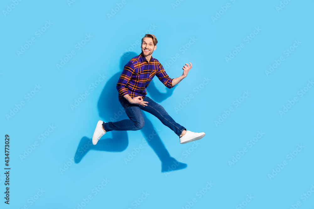 Full body photo of happy cheerful funny young man play imagine guitar jump up air isolated on blue color background Full body photo of happy cheerful funny young man play imagine guitar jump up air isolated on blue color background