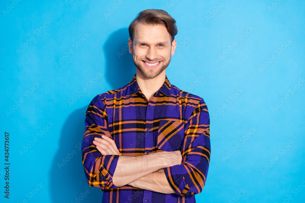 Portrait of attractive masculine cheerful guy wearing plaid shirt folded arms isolated over vivid blue color background