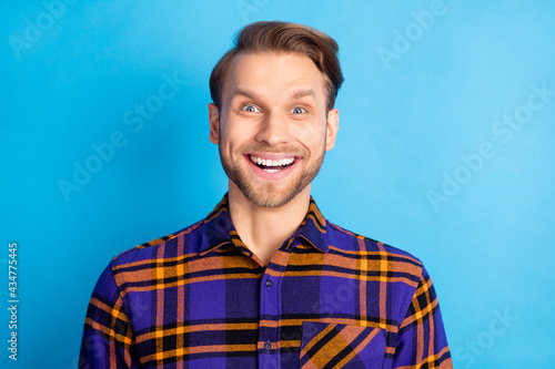 Portrait of attractive cheerful amazed glad man good mood wearing checked shirt isolated over bright blue color background