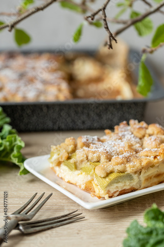 Kuchen mit Rhabarber und Streusel aus einem Blech auf einem Tisch aus hellem Holz