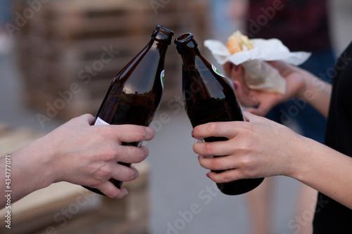 beer bottles raised for a toast. Hands of women clinking bottles.
