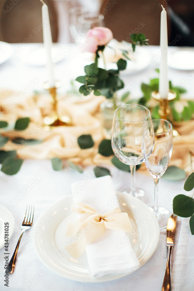 Festive table setting in gentle pastel colors. Plate and glasses close up. Gala dinner in honor of birthday or wedding. Selective focus. Festive table setting in gentle pastel colors. Plate and glasses close up. Gala dinner in honor of birthday or wedding. Selective focus.