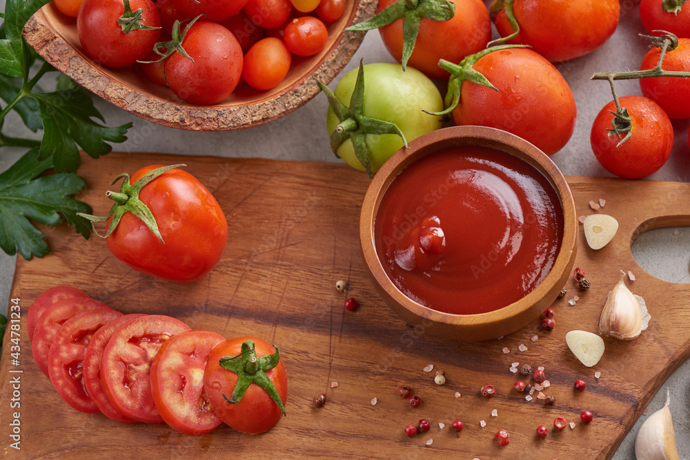 tomato sauce with garlic and vibrant green leaves of the italian parsley plant. tomato ketchup sauce in a bowl with spices, herbs and cherry tomatoes. top view. tomato sauce with garlic and vibrant green leaves of the italian parsley plant. tomato ketchup sauce in a bowl with spices, herbs and cherry tomatoes. top view.