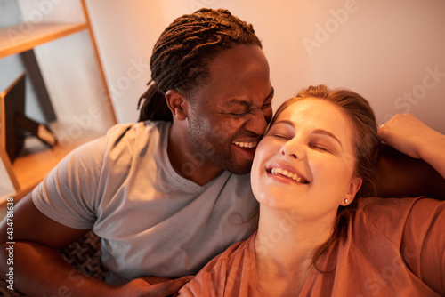 Man with dreadlocks laughing and bonding to his lovely caucasian wife © Yakobchuk Olena