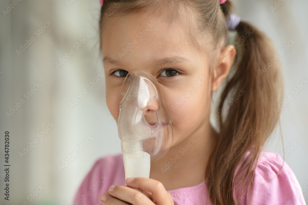 Portrait of sick little girl holding inhaler