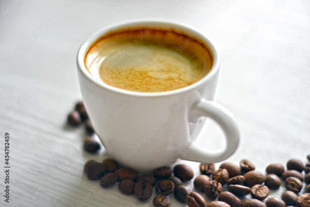 A cup of fresh coffee with coffee beans on the table A cup of fresh coffee with coffee beans on the table