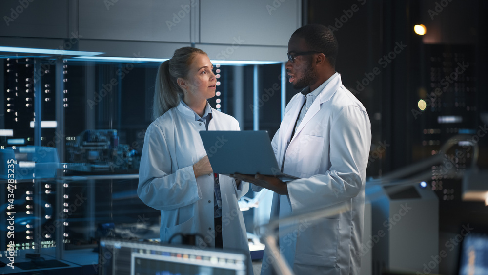 Modern Electronics Research, Development Facility: Engineer and Scientist Standing In High-Tech Laboratory, Use Laptop Computer, Talk, Design Silicon Microchips, Semiconductors, Manufacture Computers Modern Electronics Research, Development Facility: Engineer and Scientist Standing In High-Tech Laboratory, Use Laptop Computer, Talk, Design Silicon Microchips, Semiconductors, Manufacture Computers