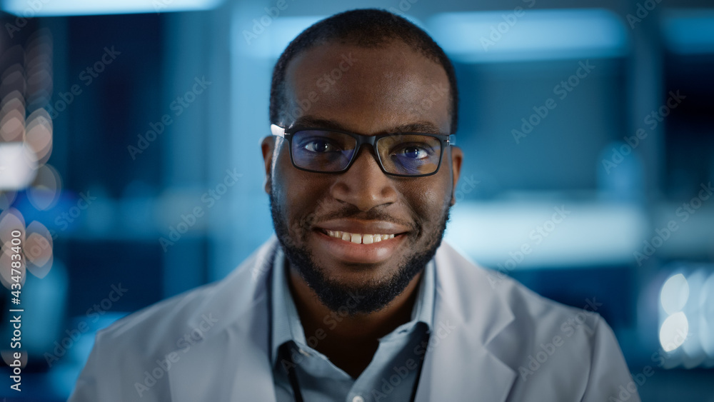 Handsome Black Man Wearing Glasses Smiling Charmingly Looking at Camera. Young Intelligent Male Engineer or Scientist Working in Laboratory. Technological Bokeh Blue Background. Close-up Shot Handsome Black Man Wearing Glasses Smiling Charmingly Looking at Camera. Young Intelligent Male Engineer or Scientist Working in Laboratory. Technological Bokeh Blue Background. Close-up Shot