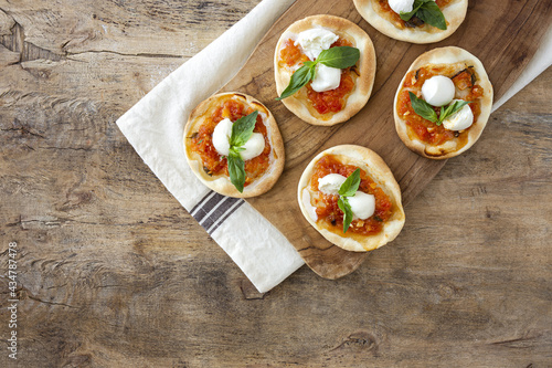 Homemade mini pizzas margarita with tomato, mozzarella and basil