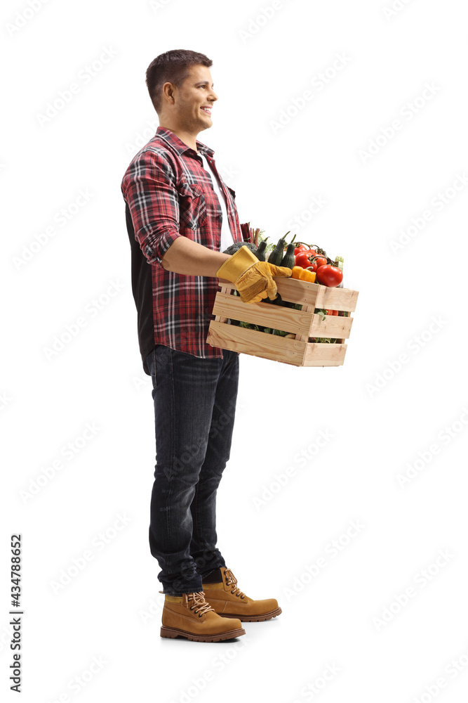 Full length shot of a farmer carrying a crate with vegetables and smiling Full length shot of a farmer carrying a crate with vegetables and smiling