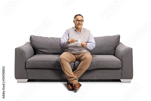 Mature man sitting on a sofa with a cup of coffee